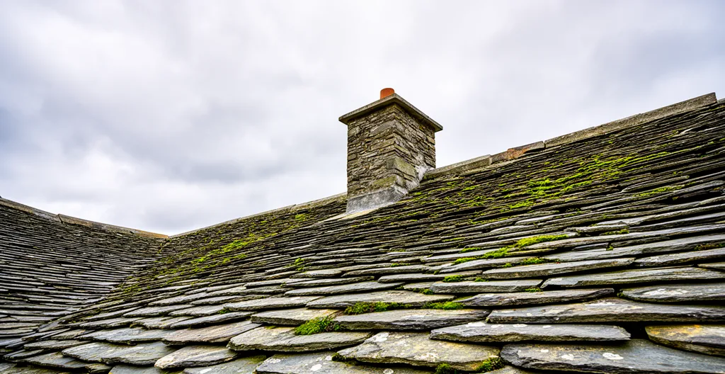 Toiture ancienne en lauze vue depuis le sol avec texture pierres de couverture Corrèze